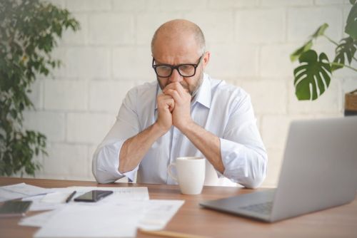 mature adult man working from office ( with laptop, paperwork, Negative Emotion)