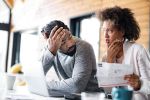 Young black couple having problems with online banking at home.