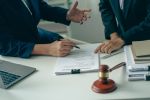 A meeting of professional business women and male lawyers working and discussing at the judge's hammered office with the scales of justice laid alongside the concept of law and consulting services.